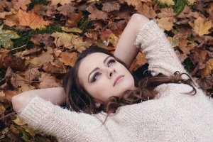 枯葉の上で寝転んでどうしようか考える女性